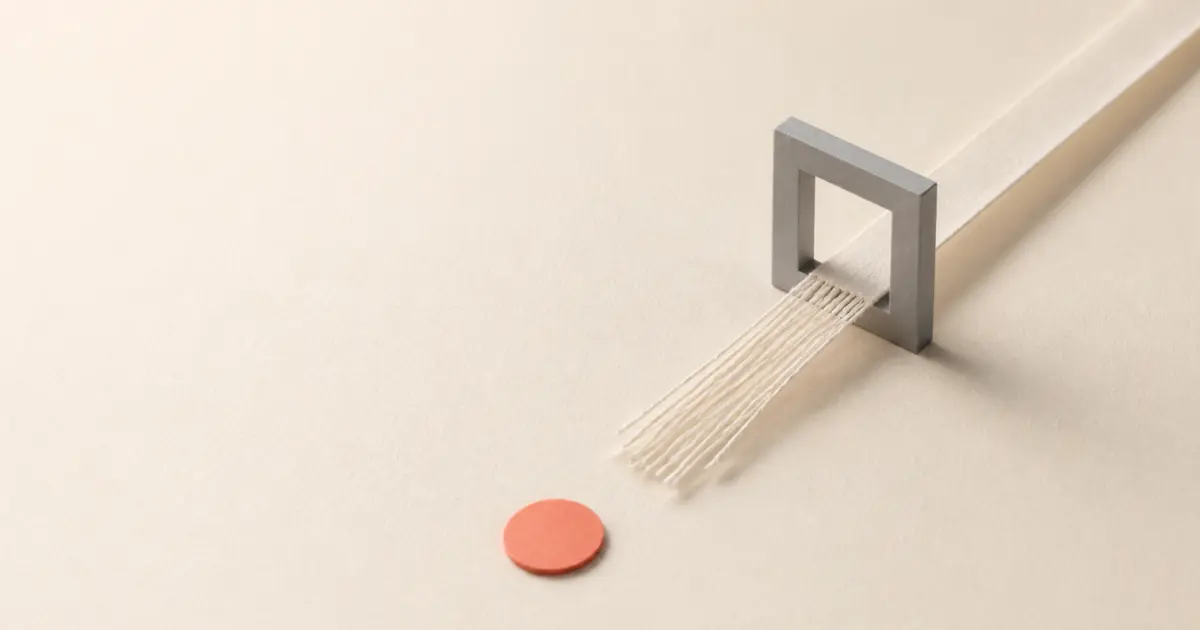 Link in bio failure concept: a smooth paper ribbon passes through a grey gate and emerges frayed, never reaching the coral disc beyond